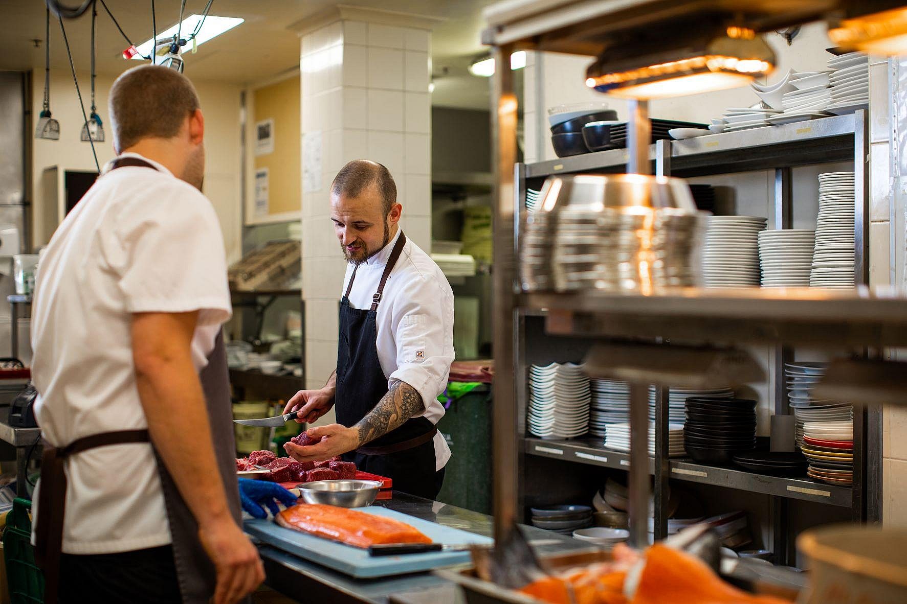 Chef and kitchen hand cooking in commercial kitchen